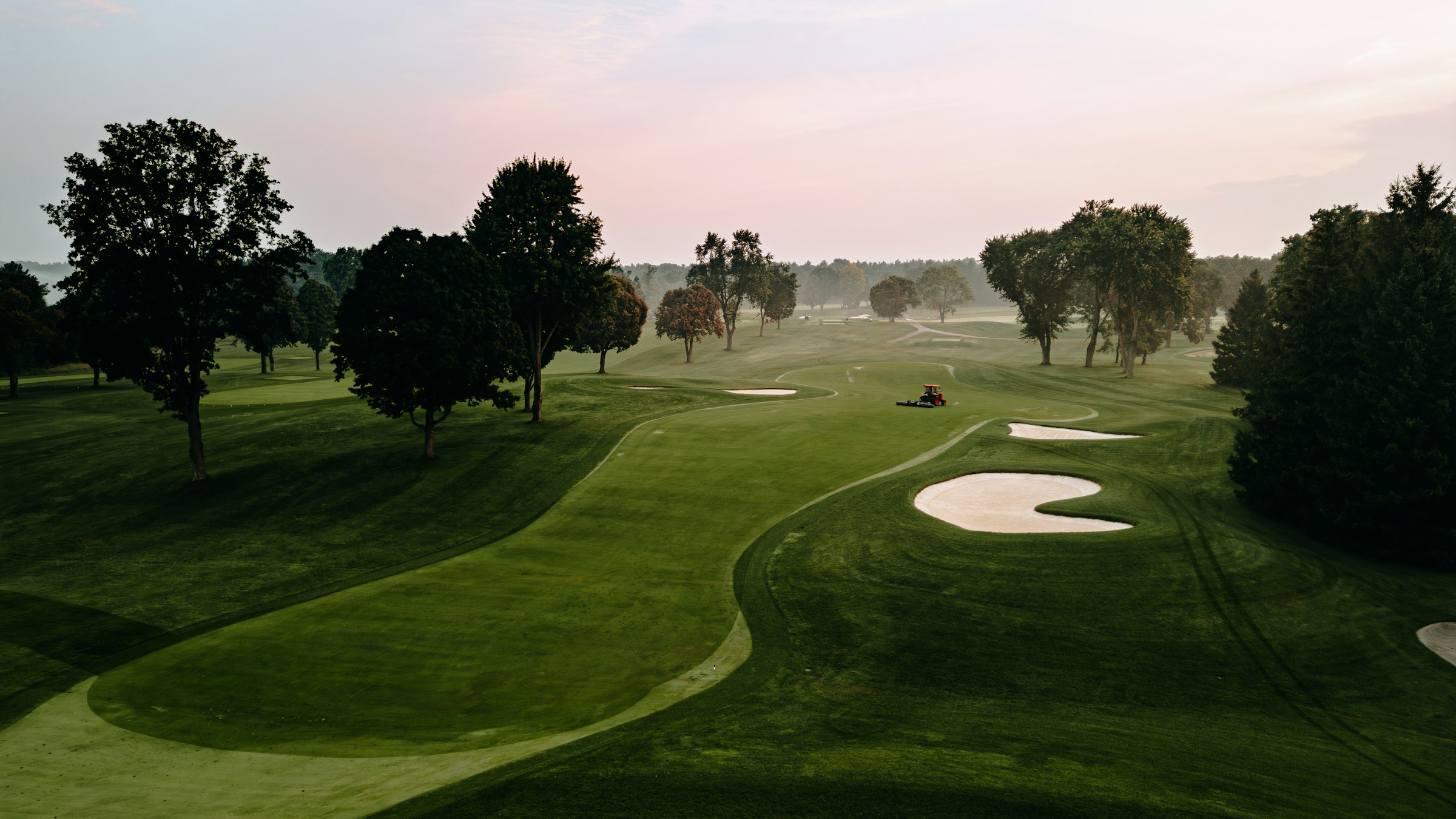 Sunlit golf course surrounded by trees